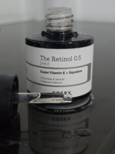 Open COSRX The Retinol 0.5 oil bottle with dropper and visible serum drops, photographed during Gentle Glow product testing.